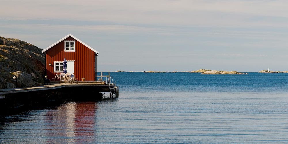 Vacker vy vid kusten som visar hav och en röd sommarstuga.